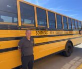 Mike Nicodemus standing in front of a school bus.